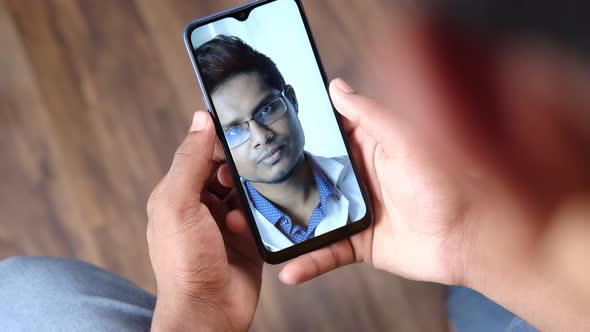 Rear View of Young Man Taking Online Consultation with Doctor on Smart Phone