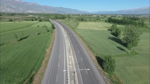 Aerial Flying Under An Empty Road Through Green Landscape alt