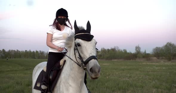 the Girl Jumps on a Horse in a Protective Mask