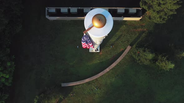 top down drone view above a white flag pole with a gold knob on top with an American flag draped dow