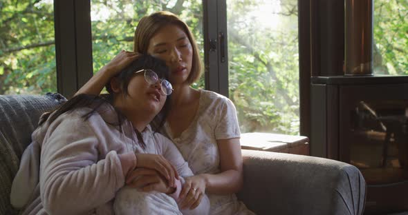 Asian mother and daughter embracing and lying on couch