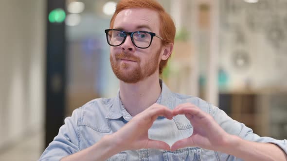 Loving Young Redhead Man Showing Heart Sign