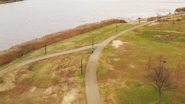 a bird's eye view over a person walking along a paved walkway, on a cloudy day in Flushing Meadows C