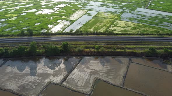 Aerial sliding over railway surrounded by paddy field