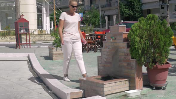 On Street in City of Perea, Greece Young Girl Comes To the Faucet and Washes Her Hands