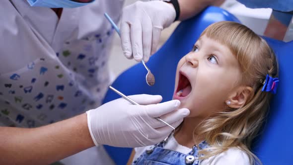 Little child in stomatology chair - close up. Cute blonde girl opened her mouth for teeth check up. 