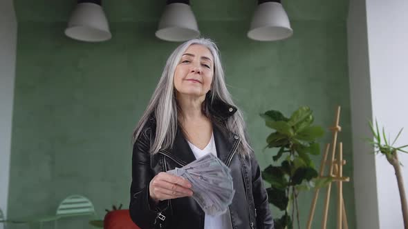 Smiling Retired Modern Woman in Stylish Clothes Posing on Camera with Dollars Banknotes