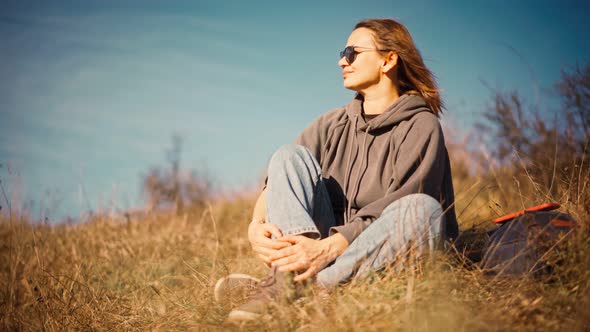 Portrait of a Young Adult Woman Wearing Sunglasses Sitting on the Hill