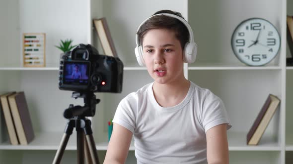 Boy Videoblogger in Headphones Filming New Vlog Video with Professional Camera at Home