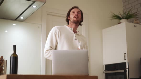 Pensive long-haired man drinking wine and talking