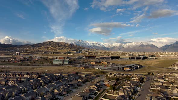 Descending over a city with office building and suburban homes against a background of snow-capped m