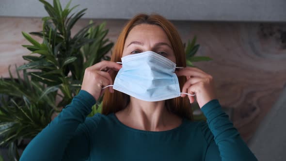 Young Woman Takes Medical Mask at Home. Health Care and Medical Concept. Close Up Portrait