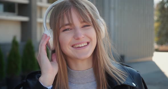 Happy Blonde Woman Listening to Music From Smart Phone Standing in Outdoor