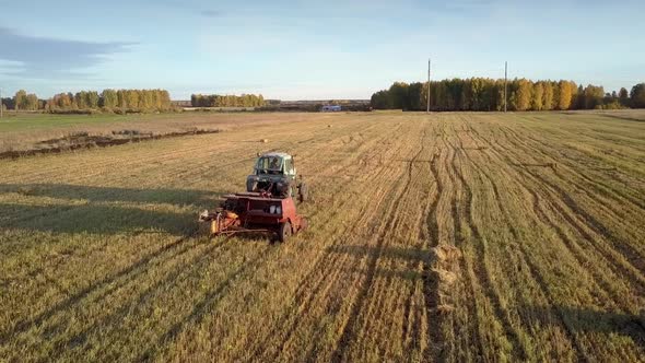 Tractor Draws Baler Pushing Up Square Bales on Field