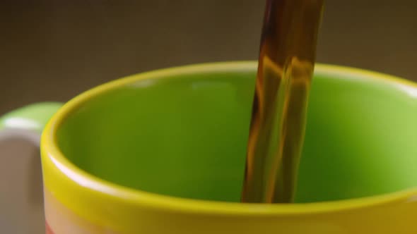 PAN RIGHT, Black coffee is poured into a colourful mug, left steaming. 60fps