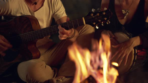 Friends Speaking Smiling Playing on Instruments Sitting Near Bonfire at Night Beach