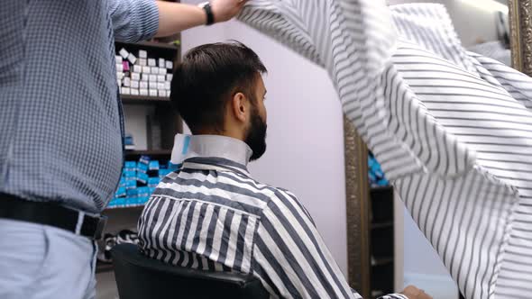 Professional Barber Prepares the Client for a Haircut. Modern Small Business Concept. Reopening of