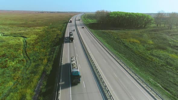 Trucks and Cars Drive Along the Highway