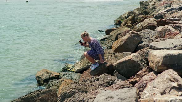 Beautiful Girl Takes Pictures of Crabs on the Seashore