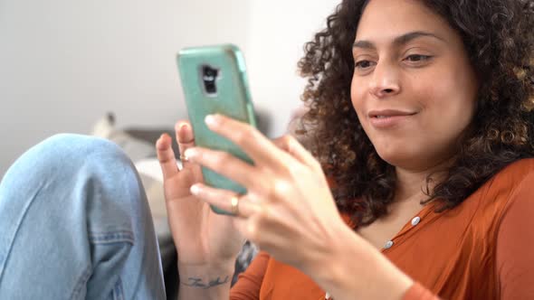 Smiling woman using smartphone at home