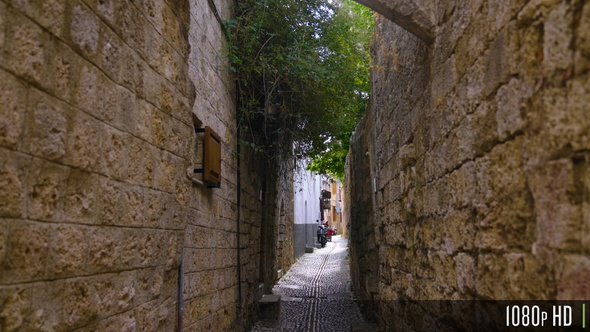 Narrow alley in an old town in Europe with old stones, cobblestones, and motorcycles