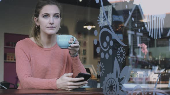 Young adult woman looking at smart phone in café