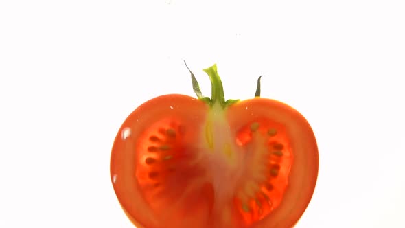 Throwing fresh cut red tomato in water