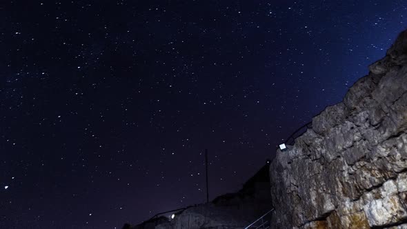 Timelapse of a Night Summer Sky and Bright Stars Rotating Filmed From Below Next to Stone Wall