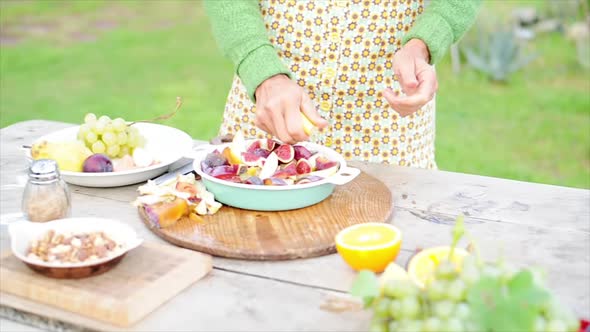 Woman squeezing citrus over cut-up fruits