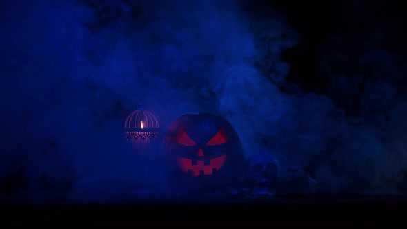 Scary laughing pumpkin and an old skull over the frightening gothic background.