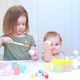 Two Sisters are Sitting at the White Table and Painting Easter Eggs - VideoHive Item for Sale