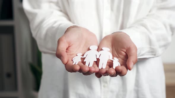 The Hands Of A Young Asian Woman Hold A Cut Out Family From White Paper A Symbol Of Family