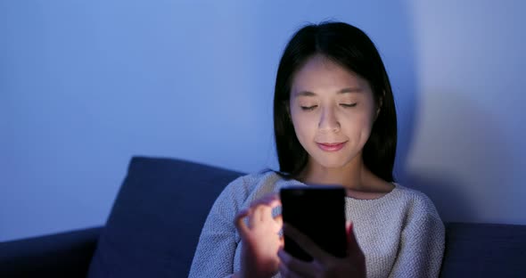 Woman use of mobile phone at home in the evening