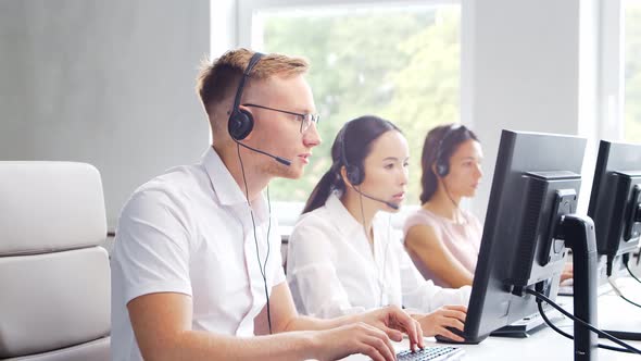 Diverse team of young professionals is working in the phone support office.