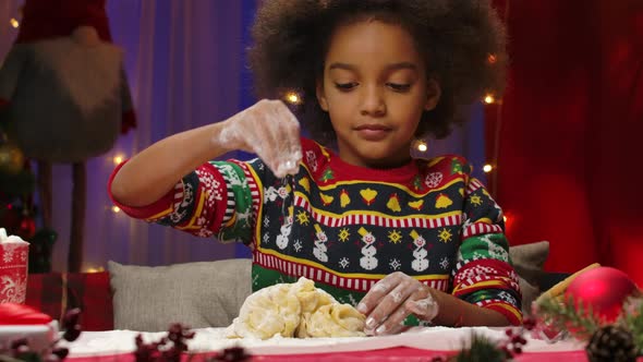 Little African American Girl in a New Years Print Sweater Prepares Dough for Homemade Cookies