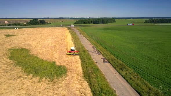 Aerial Motion Above Harvesting Combine and People on Field