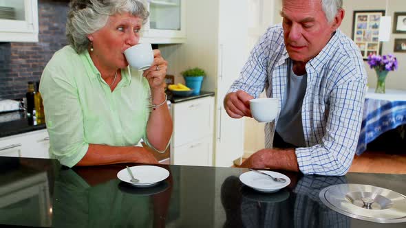 Happy senior couple having coffee in kitchen 4k