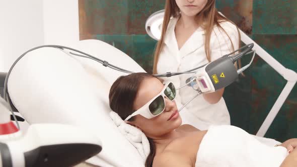 Cosmetologist Using Neodymium Laser on Female Face
