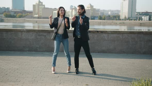 Mixed Race Man and Woman Dancing Outdoors Smiling Fooling Around Against Urban Background
