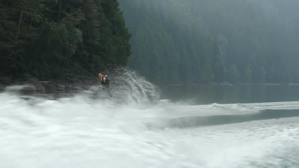 Front view of caucasian young man doing tricks on wakeboard in the city river 4k