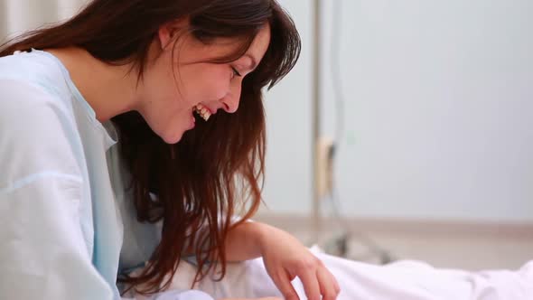 Mother sitting on a bed while smiling to a new born baby