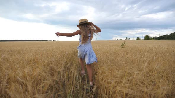 Cute Child with Long Blonde Hair Running Through Wheat Field, Little Kid in Straw Hat Jogging Over