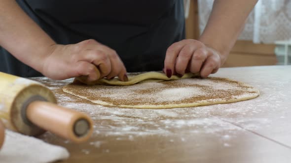 Close-up Women's Hands Rolling Up Dough with Cinnamon and Sugar Baking Pastry