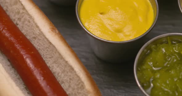 Close up slide across a juicy hot dog with an assortment of condiments.