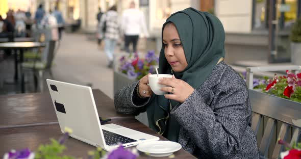 Woman in Hijab with Laptop and Coffee in Cafe