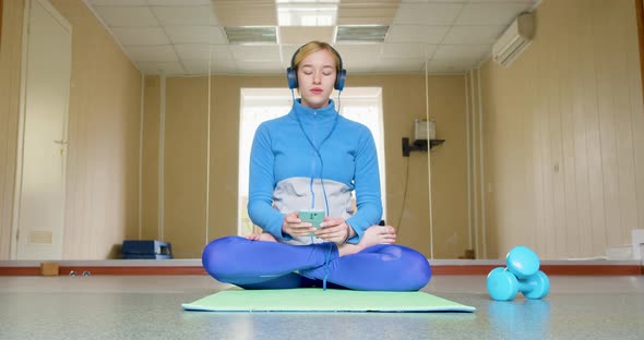 A Young Woman in Headphones Meditates to Calm Music