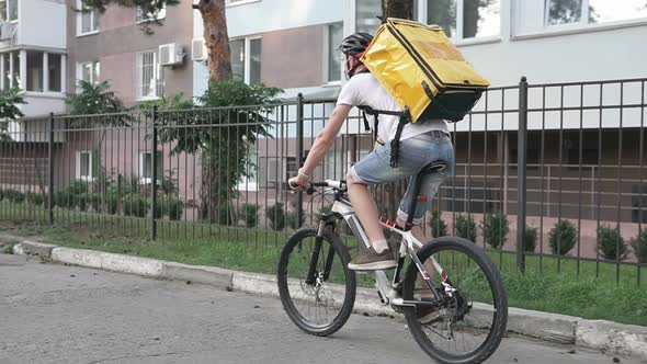 Home delivery service on a bicycle in a yellow thermo backpack