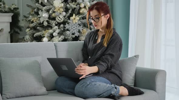 Wide Shot Portrait of Tired Confident Woman Closing Laptop with Christmas Tree at the Background