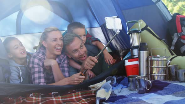 Smiling family taking selfie in the tent