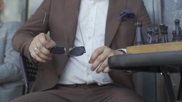 a Man in a Suit and Glasses in His Hands Sits on a Chair and Gets Up